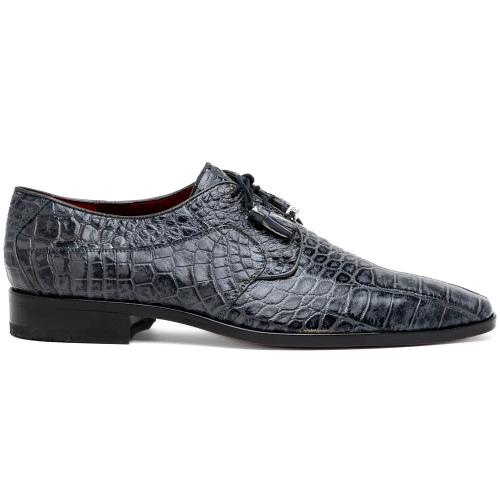 A pair of gray crocodile-pattern luxury dress shoes, the Fitipaldi Rustic Gray by Marco Di Milano, are shown—one upright and one on its side—to display a tan sole marked "Marco Di Milano." Hand-painted finishes showcase exquisite craftsmanship.