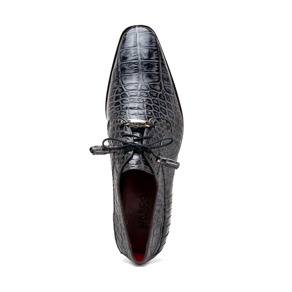 A pair of gray crocodile-pattern luxury dress shoes, the Fitipaldi Rustic Gray by Marco Di Milano, are shown—one upright and one on its side—to display a tan sole marked "Marco Di Milano." Hand-painted finishes showcase exquisite craftsmanship.