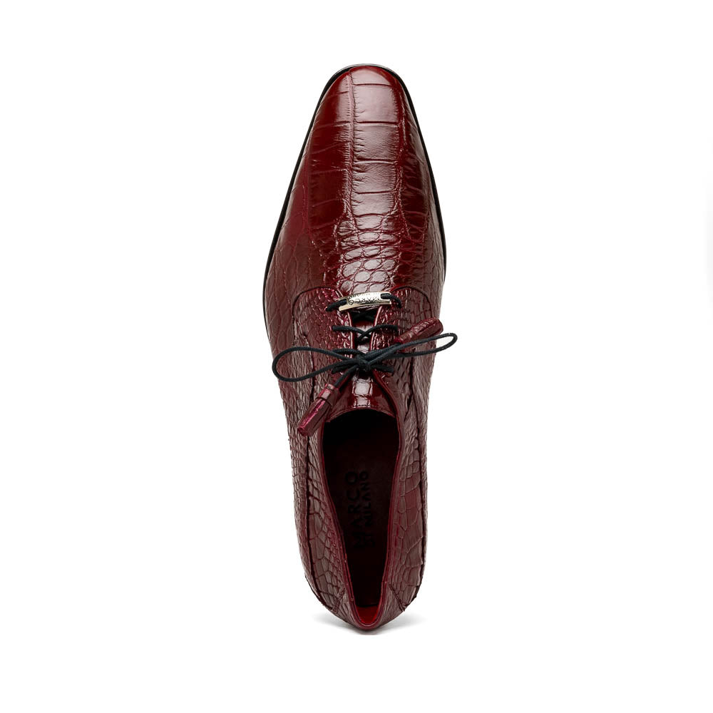 The Fitipaldi Wine by Marco Di Milano is a burgundy crocodile-pattern leather dress shoe with black laces, shown on its side to reveal the tan sole and logo—highlighting hand-painted details and luxury craftsmanship.