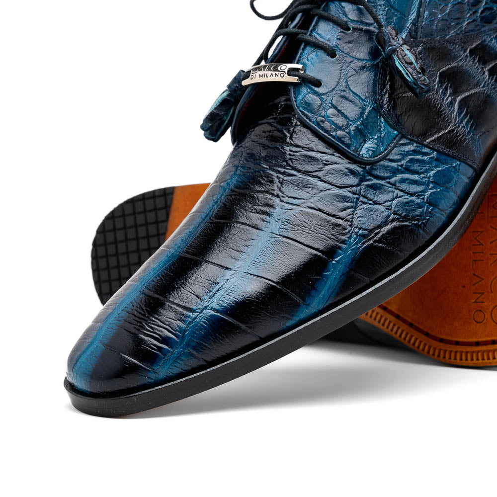 Fitipaldi Rustic Navy by Marco Di Milano: a pair of blue leather men’s dress shoes with a crocodile pattern, black soles, and lace-up fronts; one luxury shoe is shown on its side to display the tan sole.