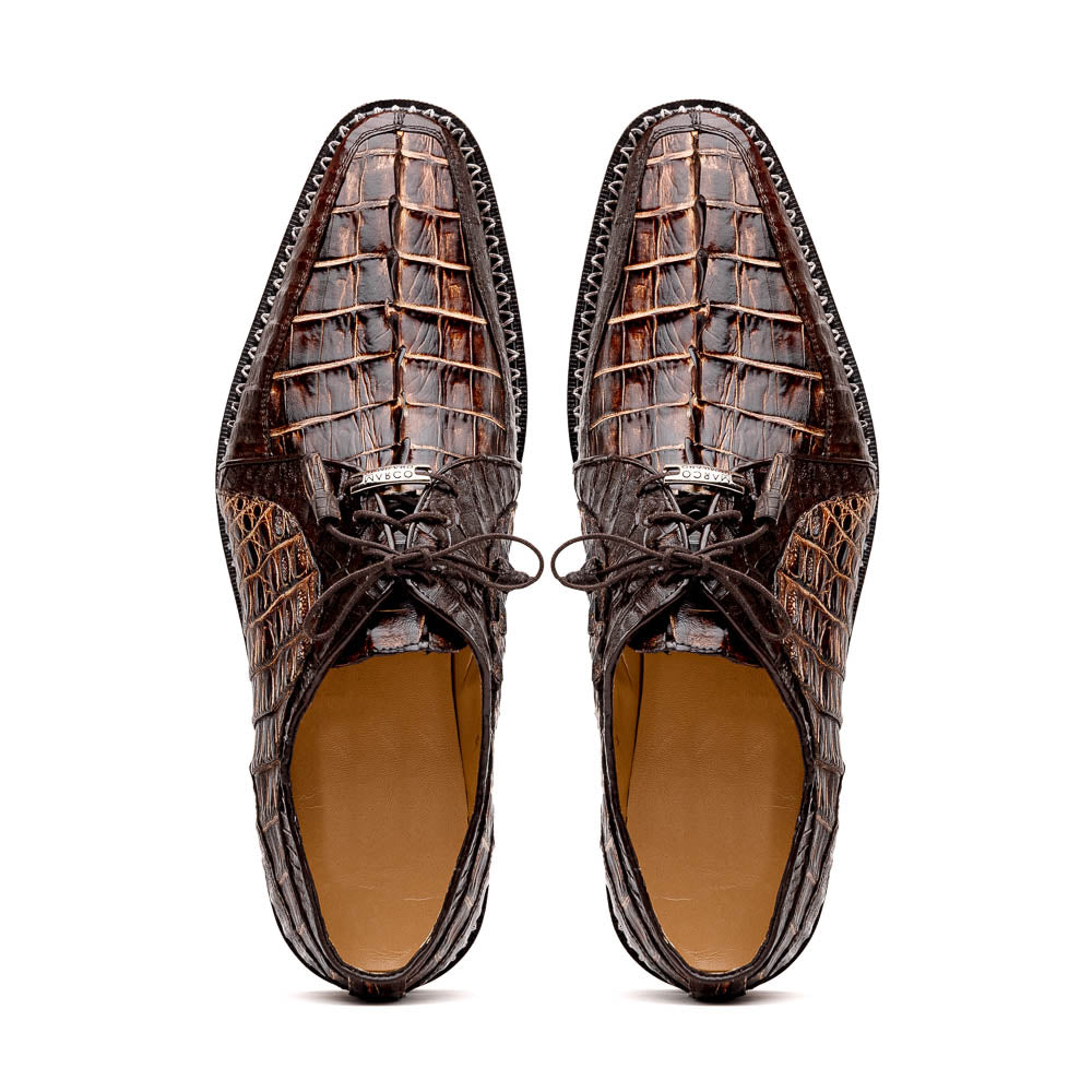 The Marco Di Milano Caribe Rustic Orix/Brown features luxury derby shoes crafted from genuine hornback caiman crocodile leather, with one upright and the other on its side showcasing a tan sole, visible stitching, and hand-painted finishes.
