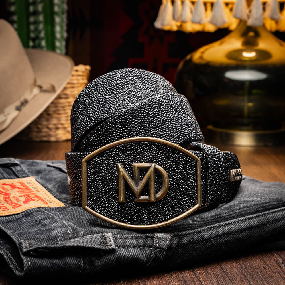 The Georgia Belt Black by Marco Di Milano is a luxury men's belt made from genuine stingray skin, featuring a bold black texture and a large gold "MD" buckle.
