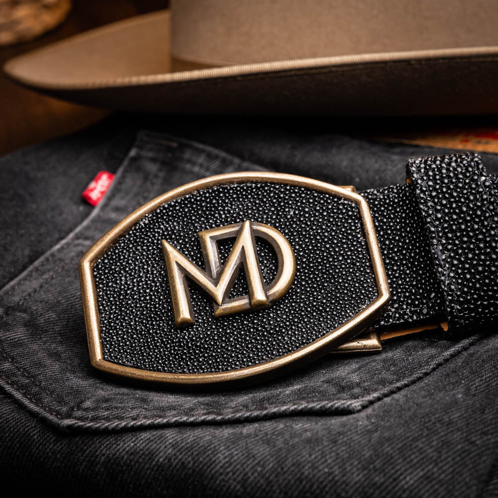 The Georgia Belt Black by Marco Di Milano is a luxury men's belt made from genuine stingray skin, featuring a bold black texture and a large gold "MD" buckle.