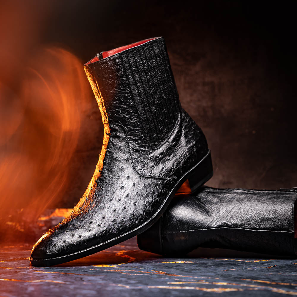 The Marco Di Milano Giorgio Black is a pair of luxury dress boots in genuine ostrich quill leather, showcasing a black ankle design, side zippers, brown leather soles, and visible sole branding—one boot upright, one on its side.