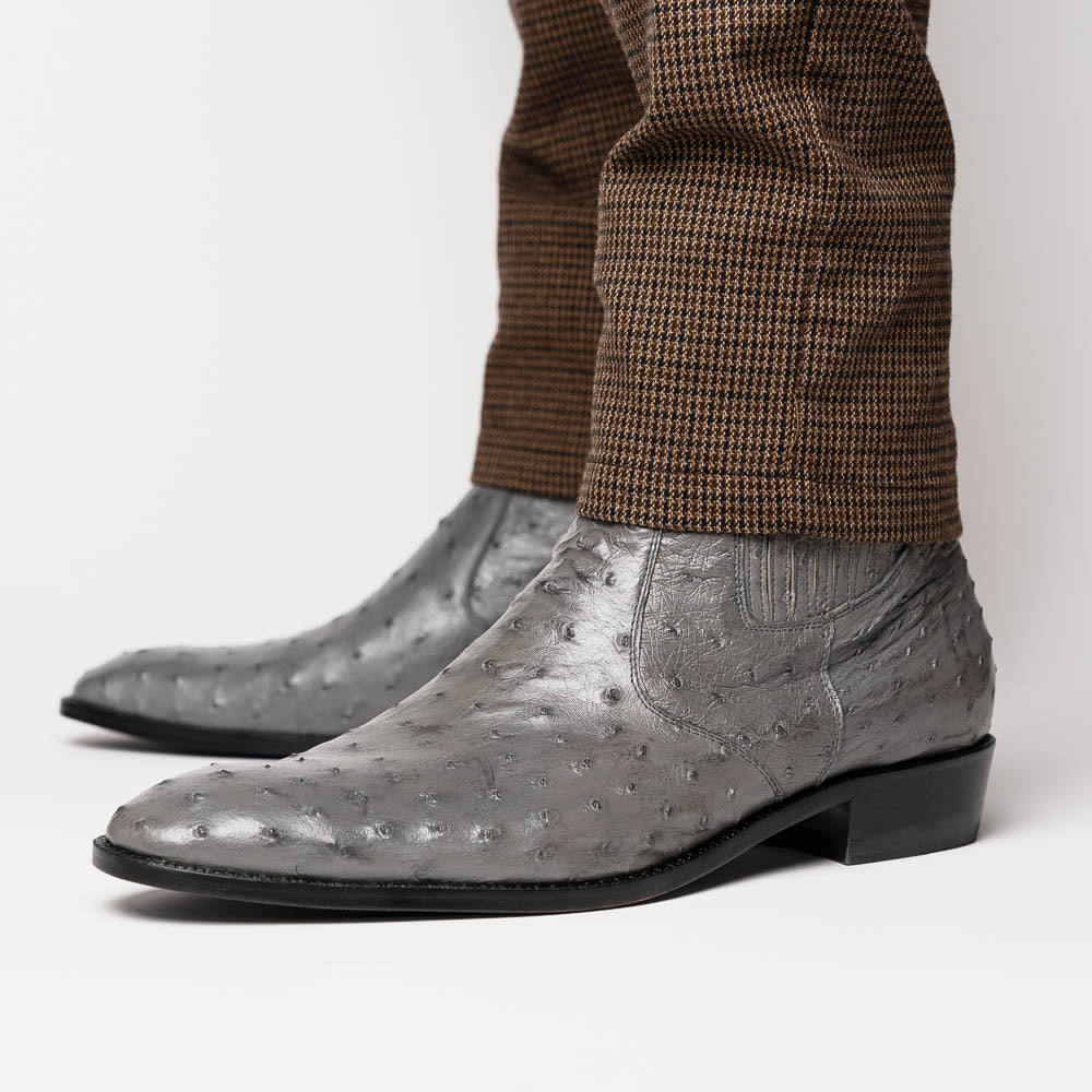 The Giorgio Serpentine Gray boots by Marco Di Milano—crafted from genuine ostrich quill leather—feature one upright and one on its side to reveal the sole, highlighting luxurious materials and exceptional craftsmanship.