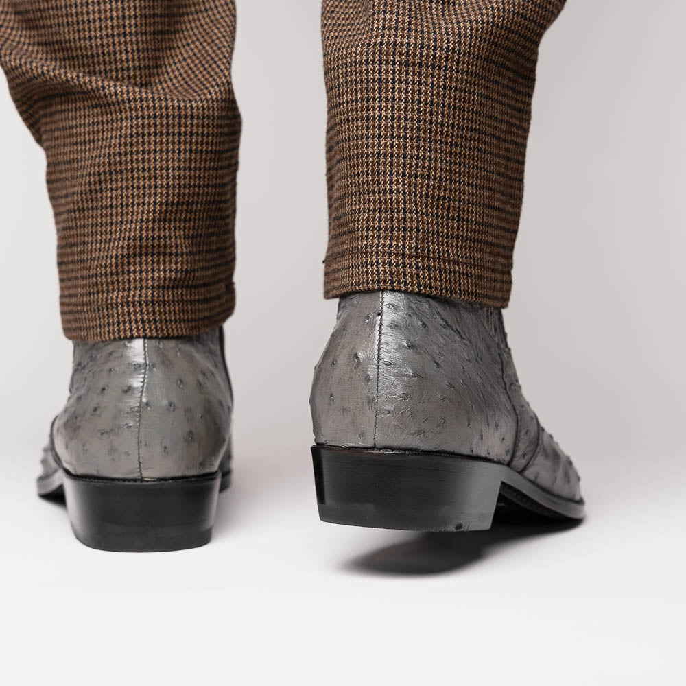 The Giorgio Serpentine Gray boots by Marco Di Milano—crafted from genuine ostrich quill leather—feature one upright and one on its side to reveal the sole, highlighting luxurious materials and exceptional craftsmanship.