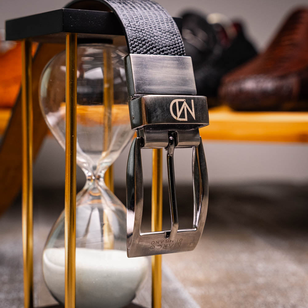 The Giovanni Belt Black by Marco Di Milano features black textured leather and a silver rectangular buckle, displayed coiled on a white background.