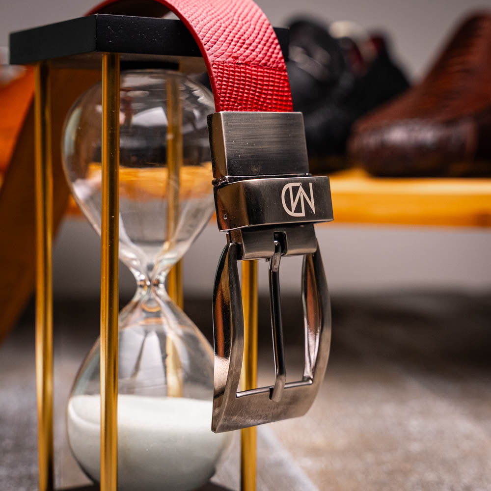 The Giovanni Belt Red by Marco Di Milano is a rolled red leather belt with a textured finish and a silver buckle, reflecting the refined style of genuine lizard ring-caiman belly belts.