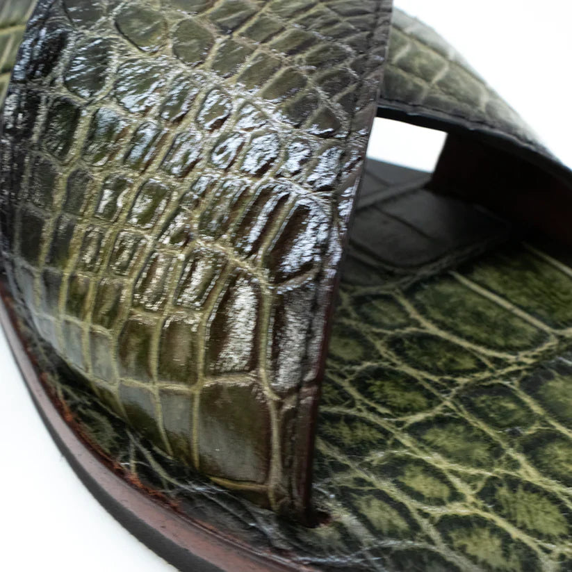 The Elios Green by Marco Di Milano is a luxurious sandal featuring green crocodile-patterned leather, crisscross straps, a flat sole, and hand-painted finishes, beautifully displayed on a white background.