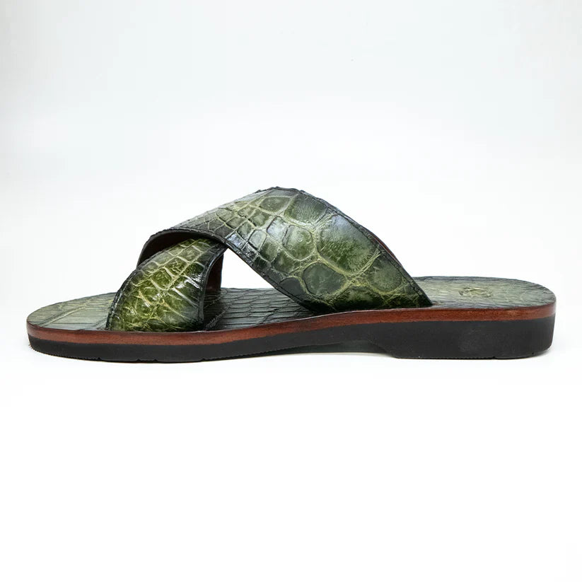 The Elios Green by Marco Di Milano is a luxurious sandal featuring green crocodile-patterned leather, crisscross straps, a flat sole, and hand-painted finishes, beautifully displayed on a white background.