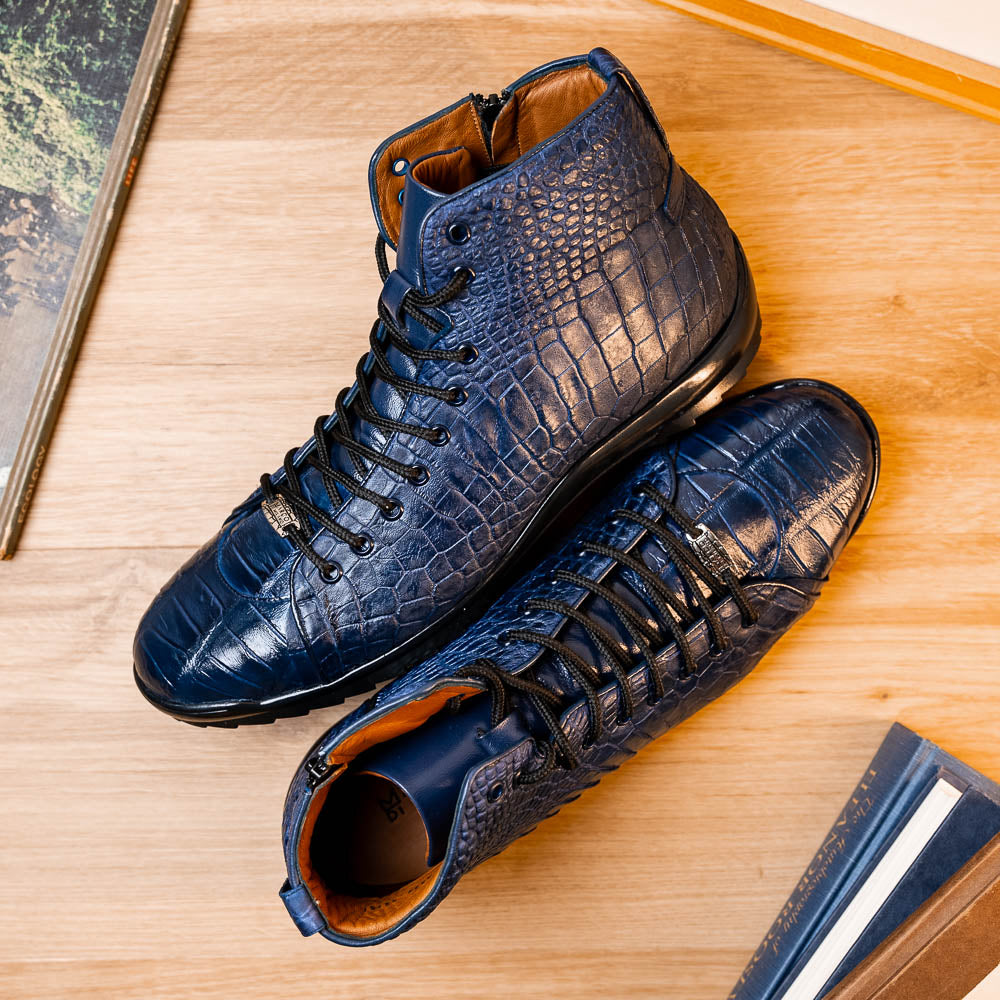 The Hermond Navy by Marco Di Milano: luxury high-top shoes in blue crocodile-patterned leather with genuine exotics, black laces, and black rubber soles—one shoe stands upright, the other lies on its side.