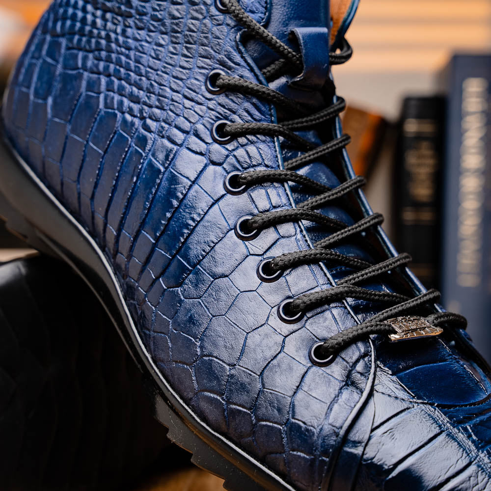 The Hermond Navy by Marco Di Milano: luxury high-top shoes in blue crocodile-patterned leather with genuine exotics, black laces, and black rubber soles—one shoe stands upright, the other lies on its side.