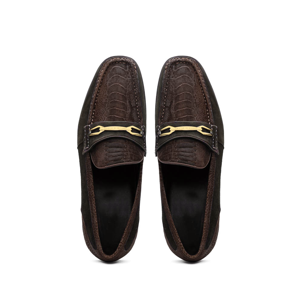 A pair of Marco Di Milano Hugo Brown sueded ostrich leg loafers with gold buckle detail and textured dark brown upper—one shoe stylishly propped on the other—epitomizes luxury footwear.