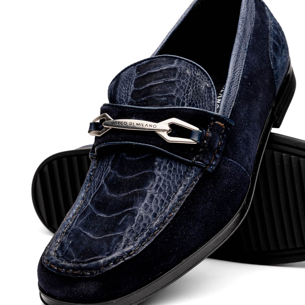 The Hugo Navy by Marco Di Milano is a pair of men's navy blue sueded ostrich leg loafers featuring a textured pattern, suede finish, and metal buckle detail—one displayed upright, the other on its side to reveal the sole.