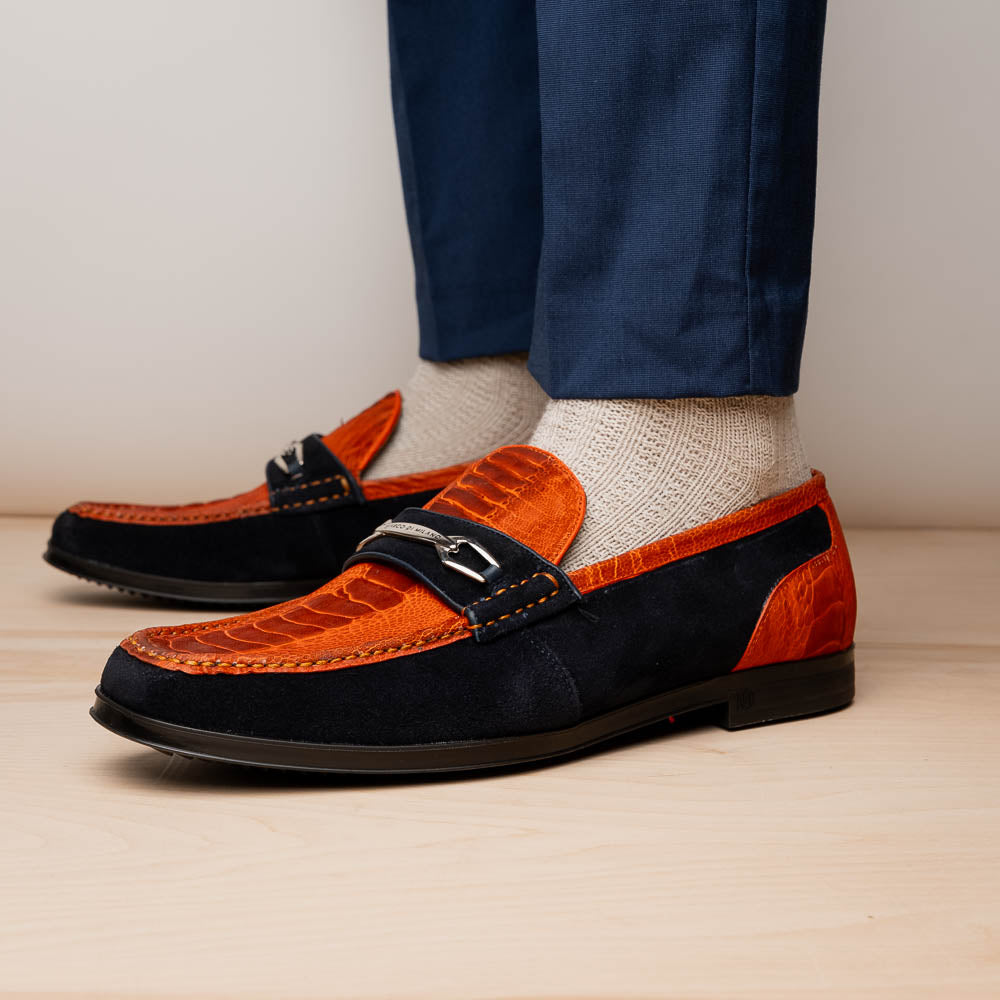 The Hugo Orange / Navy by Marco Di Milano is a men's loafer in orange crocodile-textured leather with navy suede accents, silver bit detail, and a black rubber sole with red stitching—ideal for luxury footwear fans.