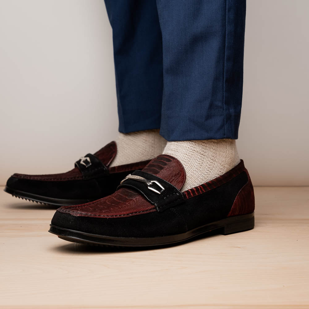 The Marco Di Milano Hugo Wine / Black men's loafers feature burgundy textured leather, black suede panels, metal buckles, and black rubber soles with red accents—luxury footwear for refined style.