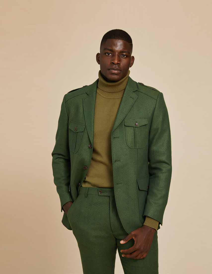 Dressed in an Inserch 4 Pocket Wool Blend Herringbone Blazer BL263-19 Olive, paired with a light turtleneck, an individual stands against a neutral backdrop, radiating contemporary sophistication.
