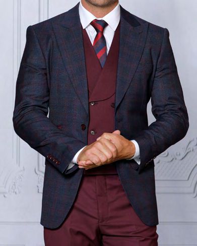 A person in a tailored fit navy suit with a matching tie and vest, clasping their hands. The INSOMNIA PARIS-1 3PC suit jacket by Insomnia is dark with a subtle pattern.