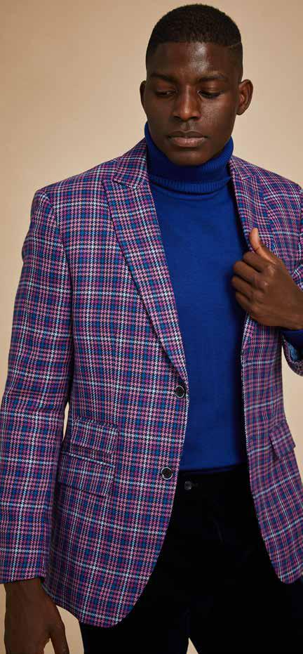 A man confidently strides against a beige background, styled in the Inserch Micro Houndstooth Check Peak Lapel Blazer BL266-126 in purple, paired with a pink turtleneck and dark pants.