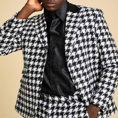 A man with gray hair and a beard is stylishly dressed in the Inserch Wool Blend Houndstooth Check Peak Lapel Blazer BL264-41 in black and white, which features modern suede trim. He elegantly pairs it with a white turtleneck sweater, black pants, and black shoes while posing against a plain background.