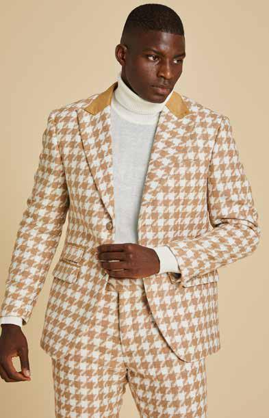 A man is wearing the Inserch Wool Blend Houndstooth Check Peak Lapel Blazer BL264-09 Khaki, paired with a beige turtleneck, gray jeans, and brown suede shoes, standing against a plain beige background.