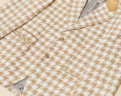 A man models the Inserch Houndstooth Suit BL264-09 Khaki by Inserch, paired with a white turtleneck, standing against a beige background and highlighting the suit's modern fit.