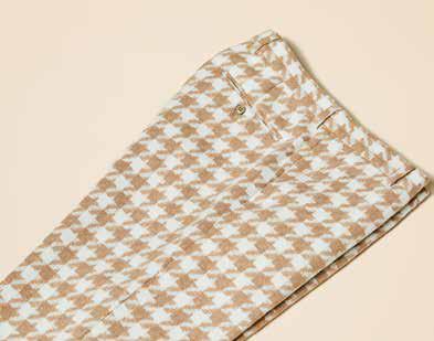 A man models the Inserch Houndstooth Suit BL264-09 Khaki by Inserch, paired with a white turtleneck, standing against a beige background and highlighting the suit's modern fit.