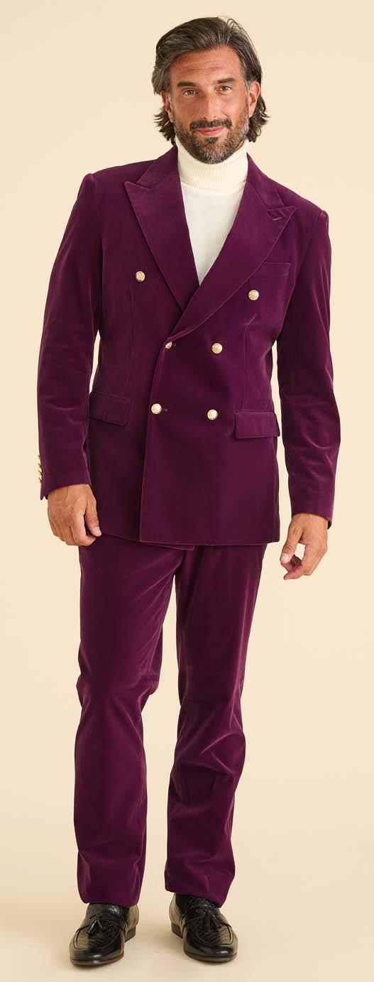 A man stands against a plain background wearing the Inserch DB Velvet Blazer BL502-166 Deep Violet by Inserch, paired with a white turtleneck and black shoes.
