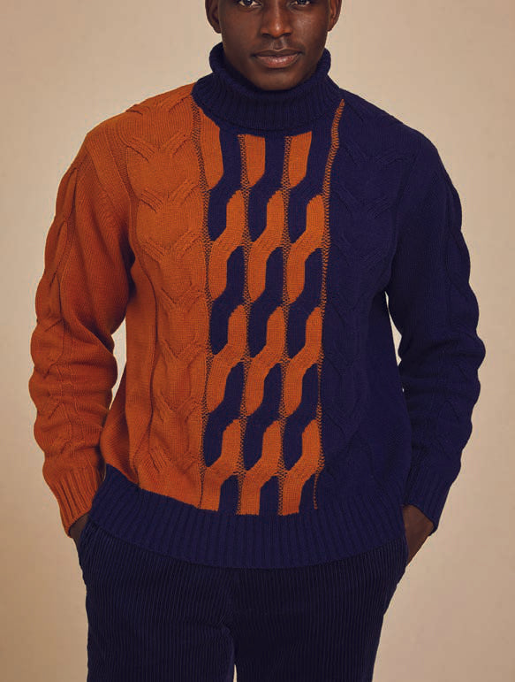 A person wearing the Inserch Cotton Blend Cable Knit Turtleneck Sweater, featuring a stylish turtleneck and sections in orange and navy blue.
