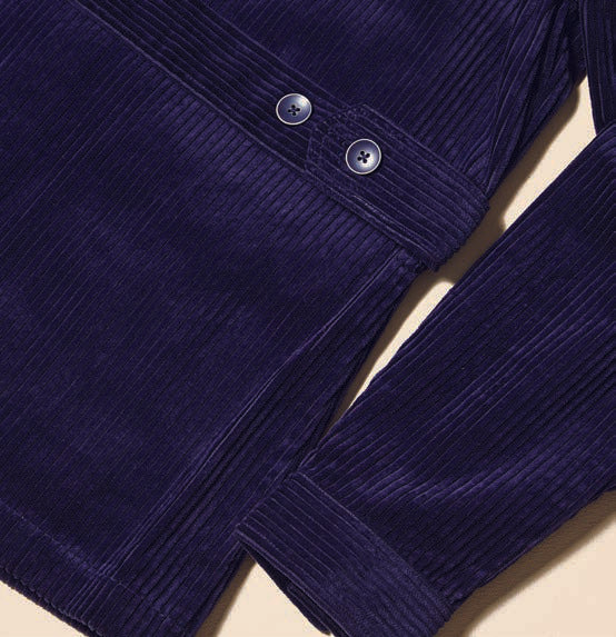 Wearing the Inserch 4-Pocket Cord Suit BL267-11 in a modern fit, complemented by an orange and blue patterned sweater, a man stands confidently against a beige background. The navy blue corduroy jacket and pants from Inserch add texture to his ensemble, highlighted by an adjustable back tab for tailored comfort.