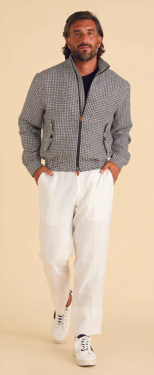 A man is dressed in the Inserch Linen Houndstooth Jacket Suit JS269-00041 Black & White, featuring a tailored jacket and pants with a small checkered pattern that evokes a classic houndstooth design.