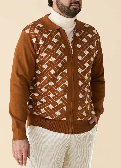 A man wears the Inserch Geometric Full Zip Sweater SW908-00005 Caramel over a white turtleneck and white corduroy pants, standing with one hand in his pocket.
