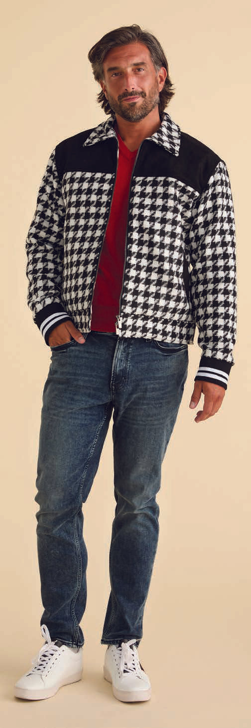An individual with a beard stands against a beige background, donning an Inserch Wool Blend Houndstooth Full Zip Bomber Jacket JS264-41 in black and white. The jacket's 2-way zipper and regular fit layer stylishly over his red shirt, blue jeans, and white sneakers.