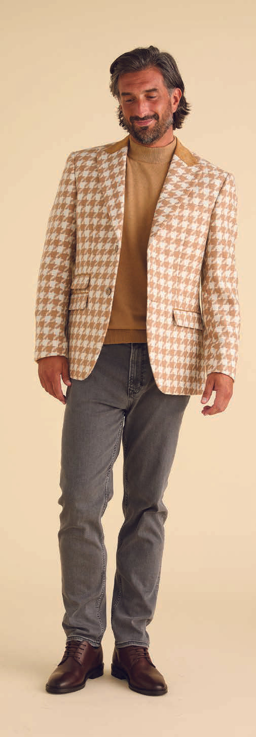 A man models the Inserch Houndstooth Suit BL264-09 Khaki by Inserch, paired with a white turtleneck, standing against a beige background and highlighting the suit's modern fit.