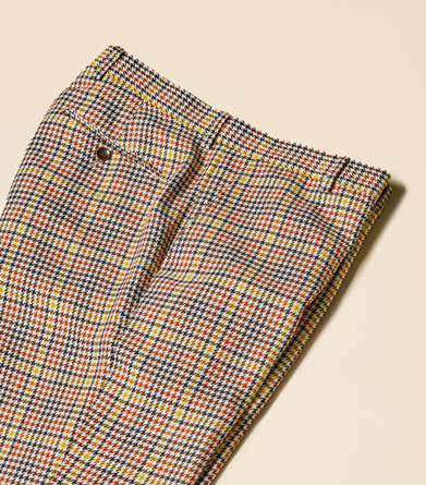 A person is showcasing a contemporary style with a yellow jacket over a brown shirt and Inserch Micro Check Pants P265-64 Mocha, paired with dark brown boots, all set against a plain background.