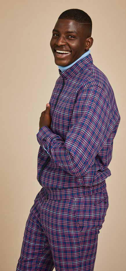 A man wearing the Inserch Micro Check Suit JS266-126 Purple, a stylish regular fit suit featuring a patterned blue and purple check design with a printed lining, smiles against a plain background.