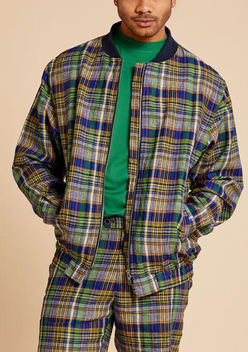 An individual wearing the Inserch Premium Linen Yarn-Dye Madras Plaid Short Zip Jacket in a multi-color pattern over a green shirt is standing against a beige background.