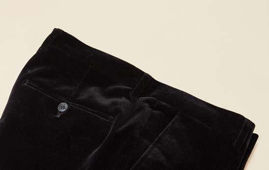 A folded pair of Inserch Velvet Pants P502-00001 in black is displayed on a beige background, showcasing a modern fit with a visible back pocket and button.
