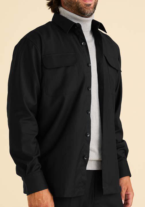 A person wearing the Inserch Two-Pocket Shirt SE004-00001 in black by Inserch, styled over a light gray turtleneck sweater, is shown from shoulders to hips against a beige background.
