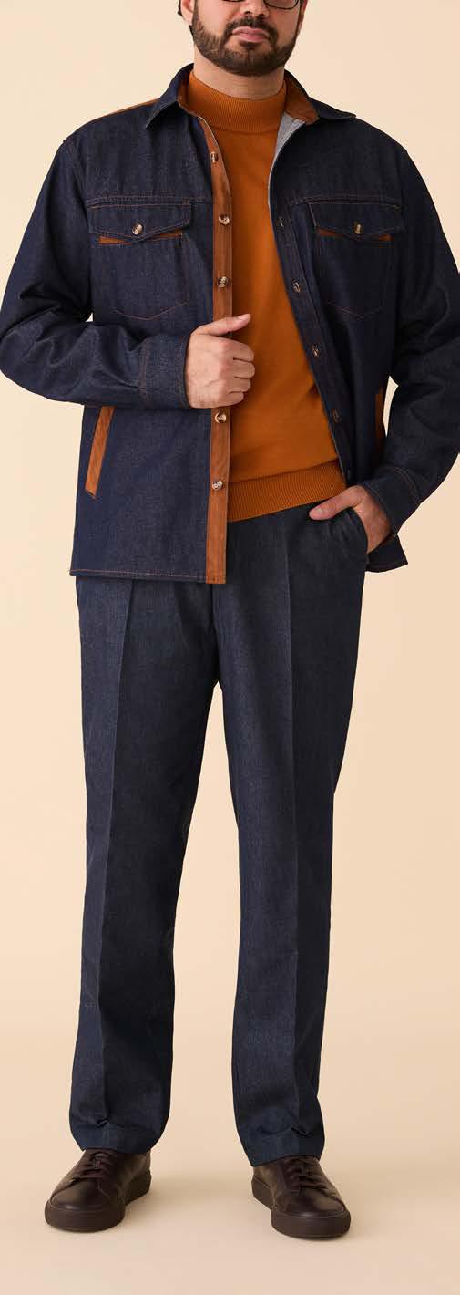 A man models the Inserch Denim Shirt Jacket w/ Suede Trim 2pc Set JS005-P005-00195 Indigo, paired with an orange-brown turtleneck sweater and brown shoes, standing against a beige background.