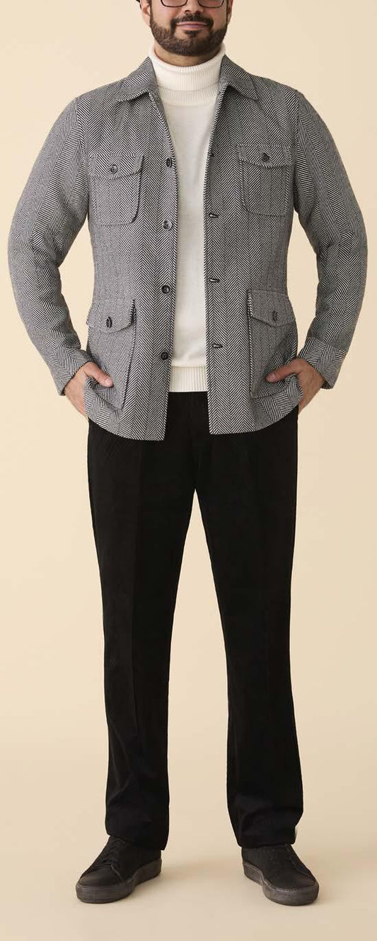 A person wearing the Inserch Herringbone 4 Pocket Jacket JS273-00041 Black/White by Inserch over a white turtleneck, black pants, and dark shoes stands against a plain beige background.