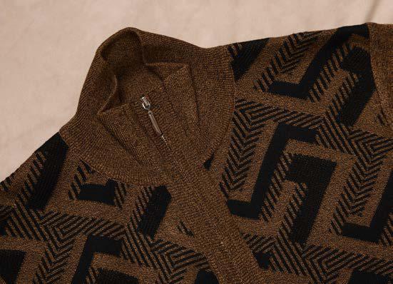 A man wearing the Inserch Full Zip Sweater SW616-00027 Aztec by Inserch—a brown intarsia sweater with a geometric black pattern—paired with a white turtleneck and brown pants, standing against a beige background.
