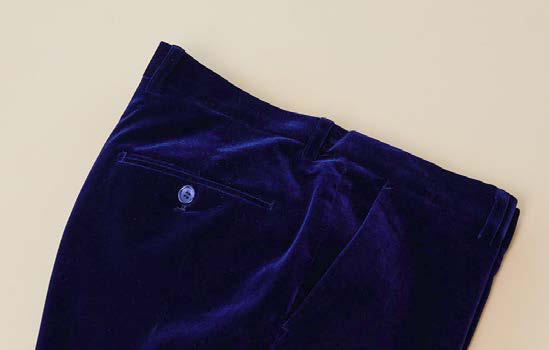 A pair of folded Inserch Velvet Pants P502-00013 in royal blue, featuring a modern fit with a flat front, back pocket, and button closure, is displayed on a light beige surface.