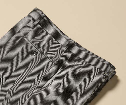 The Inserch Herringbone Pants P273-00041 Black/White by Inserch are displayed folded on a beige background, showcasing their modern fit waistband, front pleats, and belt loops.