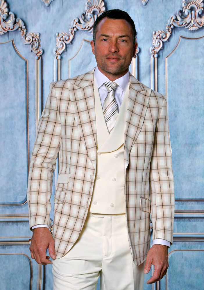 A man wearing the INSOMNIA PARIS-6 3PC Compose Tailored Fit Cream Suit by Insomnia stands in front of an ornate blue wall.