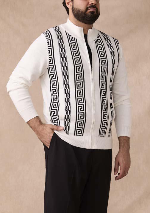 A man wearing the Inserch Greek Cable Full Zip Sweater SW617-00149 in white and black, featuring black geometric patterns, along with black pants, stands against a plain beige background.