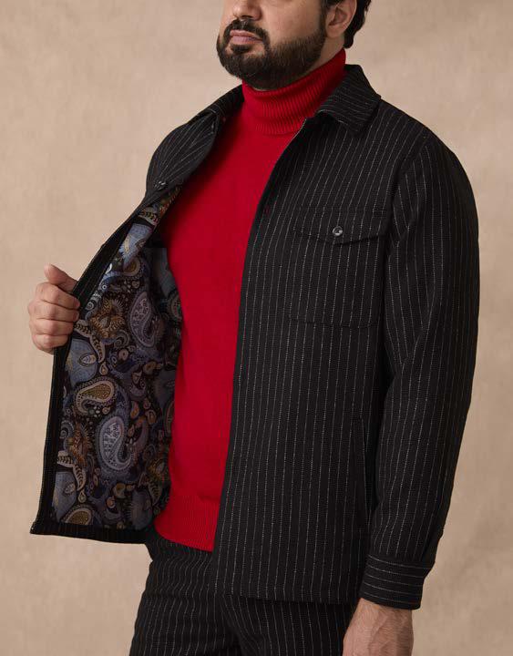 A man wears the Inserch Wool Blend Flannel Jacket JS280-00001 Black, featuring a red turtleneck underneath, as he holds the jacket open to display its paisley-patterned lining and distinctive marled buttons.