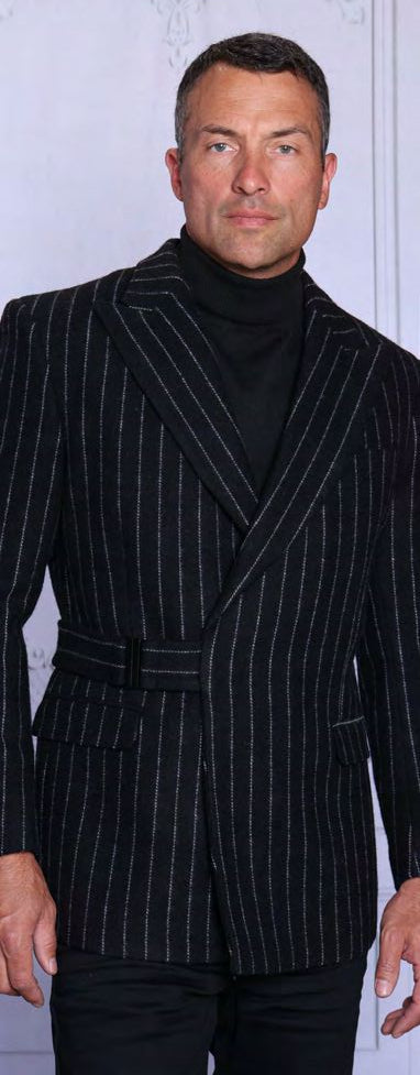 A man wearing the Insomnia INSOMNIA MZW-703 Fancy Wool Blend Black Blazer over a black turtleneck stands against a plain, light-colored background.