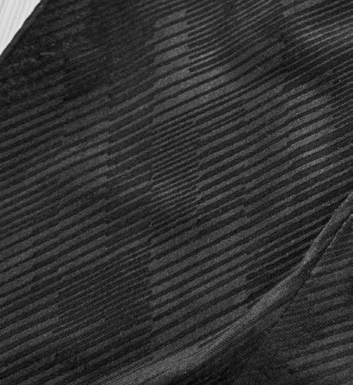 A man wearing the Inserch Velvet Diagonal Blazer BL275-00001 Black, featuring a notch collar, styled over a light gray turtleneck sweater with black pants, stands against a neutral background.