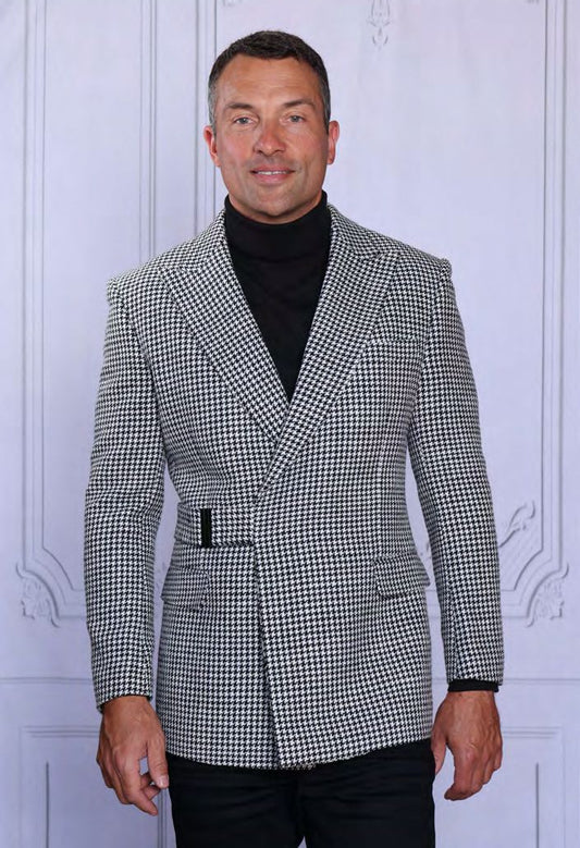 A man stands before a white paneled wall wearing a black turtleneck and the Insomnia INSOMNIA MZW-701 Fancy Wool Blend Blazer, featuring a tailored fit and black-and-white houndstooth pattern.